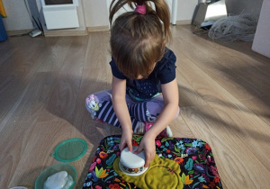 Dziewczynka ćwiczy z pomoca masy plastycznej slime.